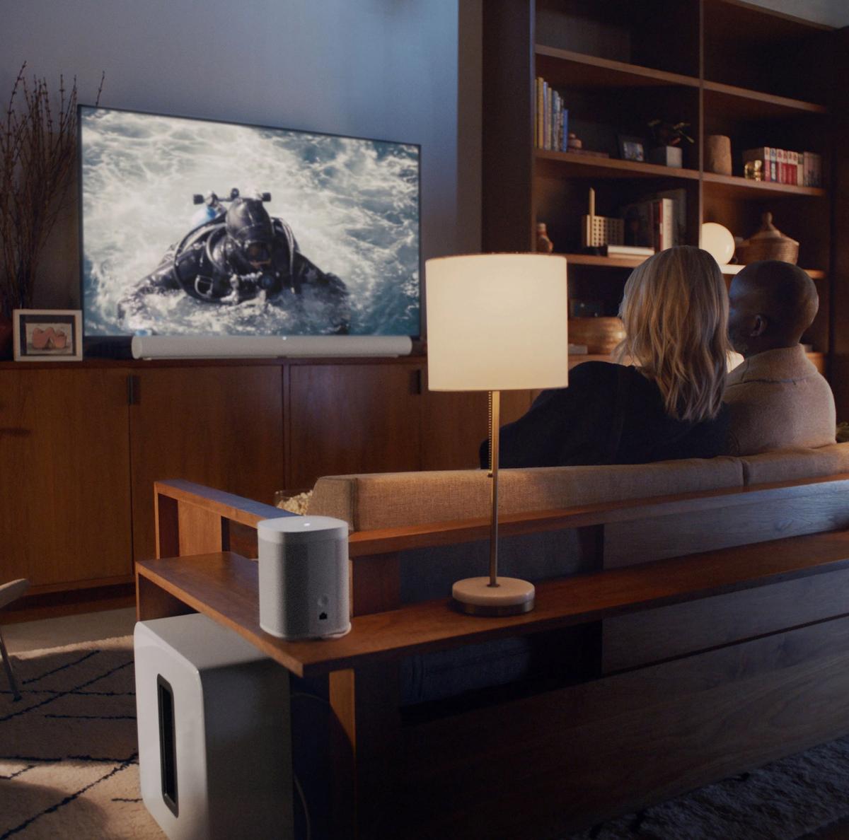 Bračni par gleda TV sa belim Sonos Arc sistemom kućnog bioskopa